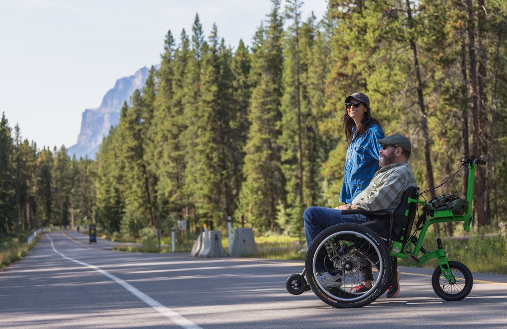 Adult couple or friends in wheelchair at Bow Valley Parkway during the summer