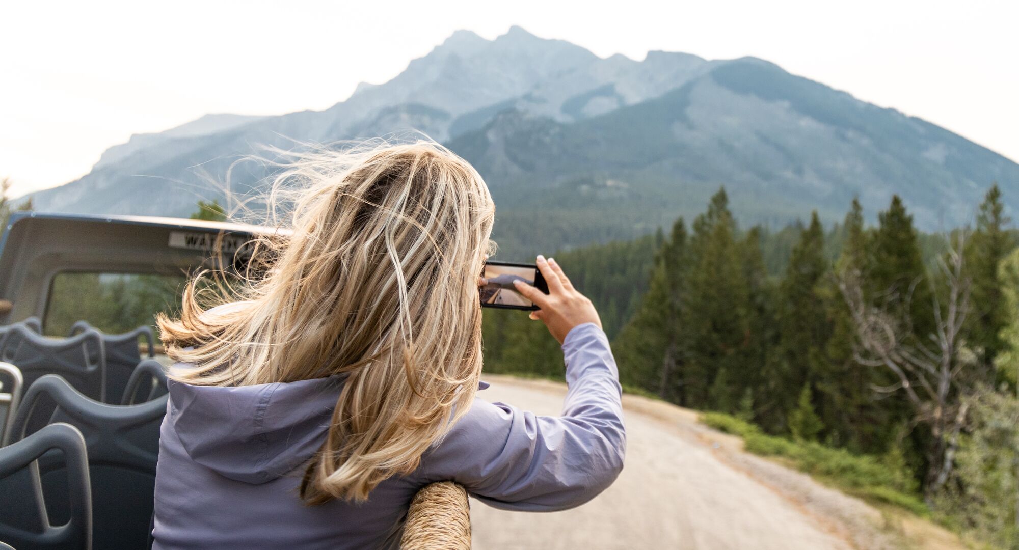 Person on a guided tour in the Banff area, taking a photo from the top of a open top bus