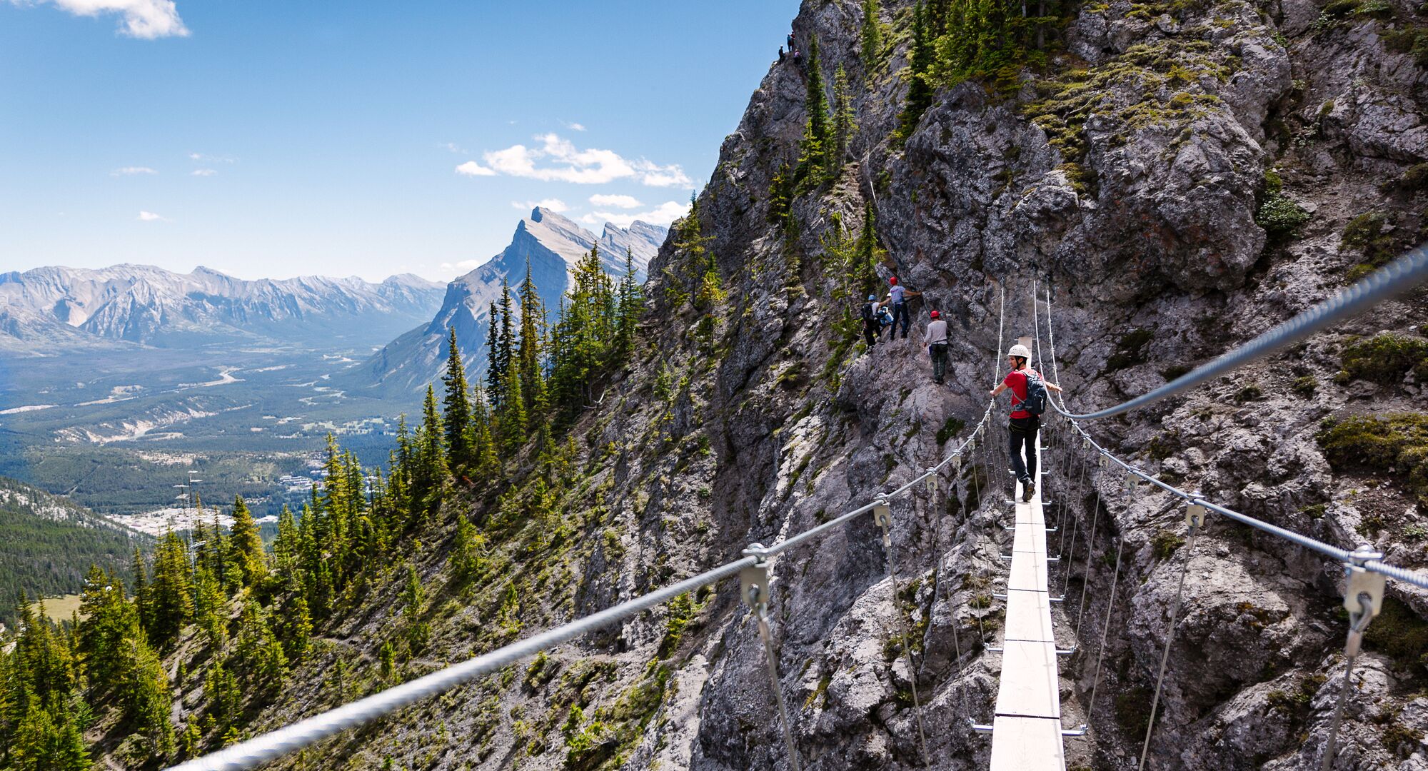 A person crossing a wooden suspension bridge at the Mt. Norquay Via Ferrata