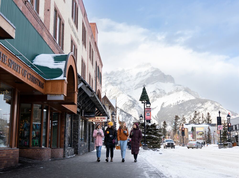 Friends enjoy a hot chocolate while shopping on Banff Ave. in the snow in Banff National Park.
