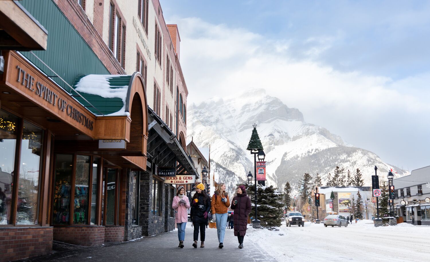Friends enjoy a hot chocolate while shopping on Banff Ave. in the snow in Banff National Park.