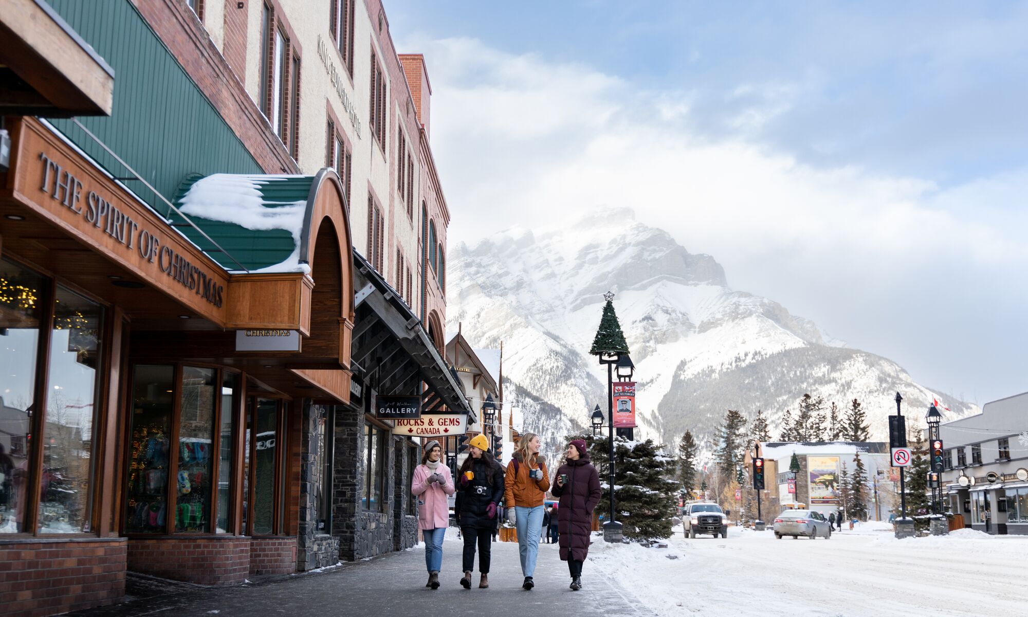 Friends enjoy a hot chocolate while shopping on Banff Ave. in the snow in Banff National Park.
