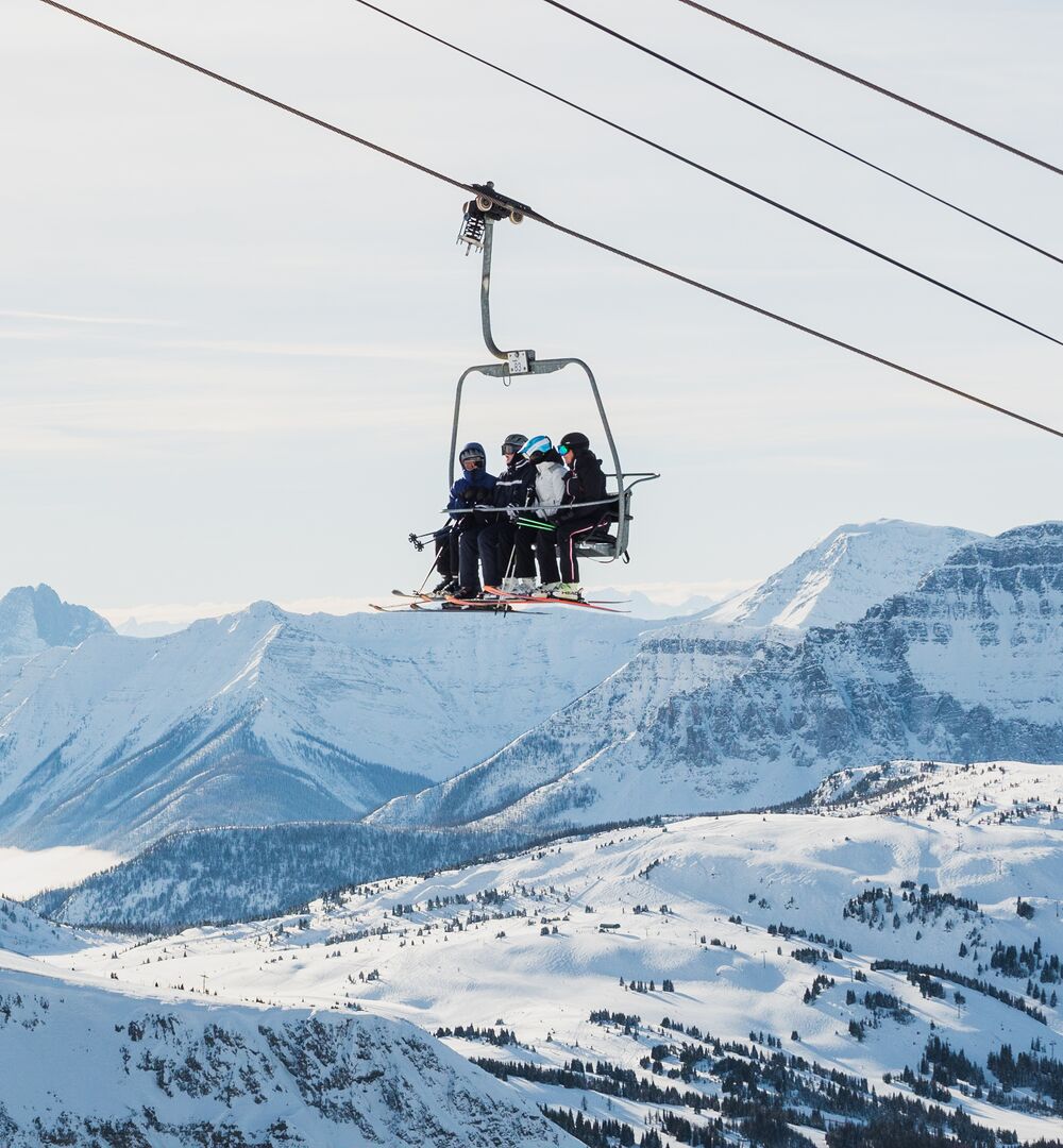 Group of four people riding a chairlift at Sunshine Village Ski Resort in Banff National Park