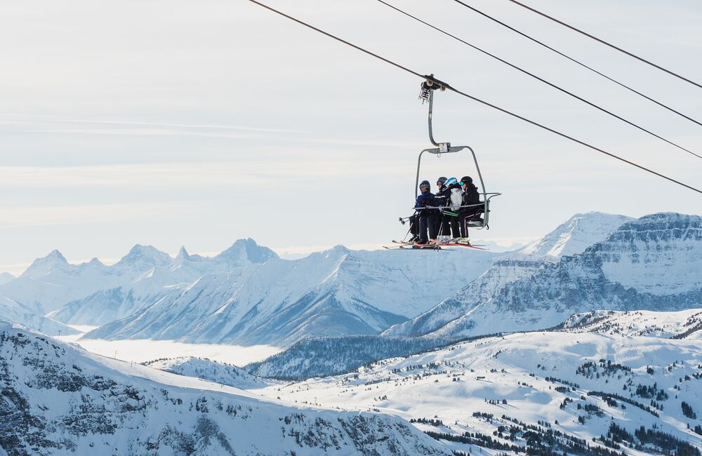 Group of four people riding a chairlift at Sunshine Village Ski Resort in Banff National Park