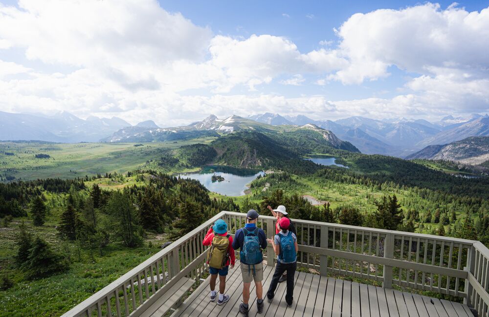 Friends stand at a lookout point, looking over Sunshine Meadows on a blue bird day in Banff National Park.