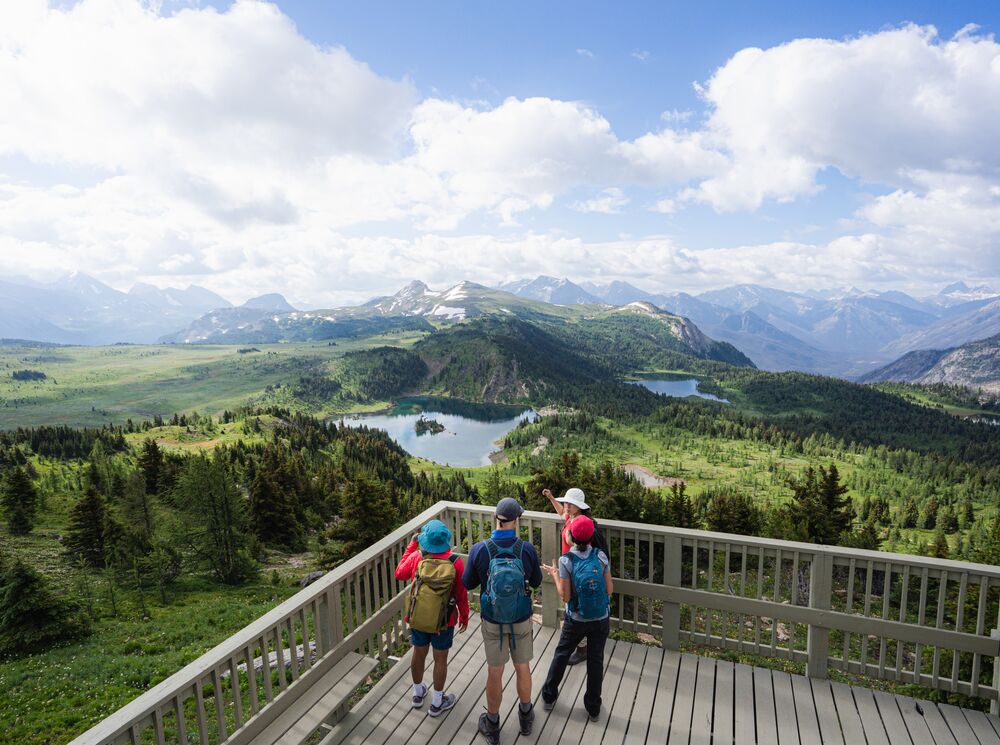 Four people on the Standish Viewing Deck at sunshine Meadows overlooking Rockbound Lake near Banff National Park.
