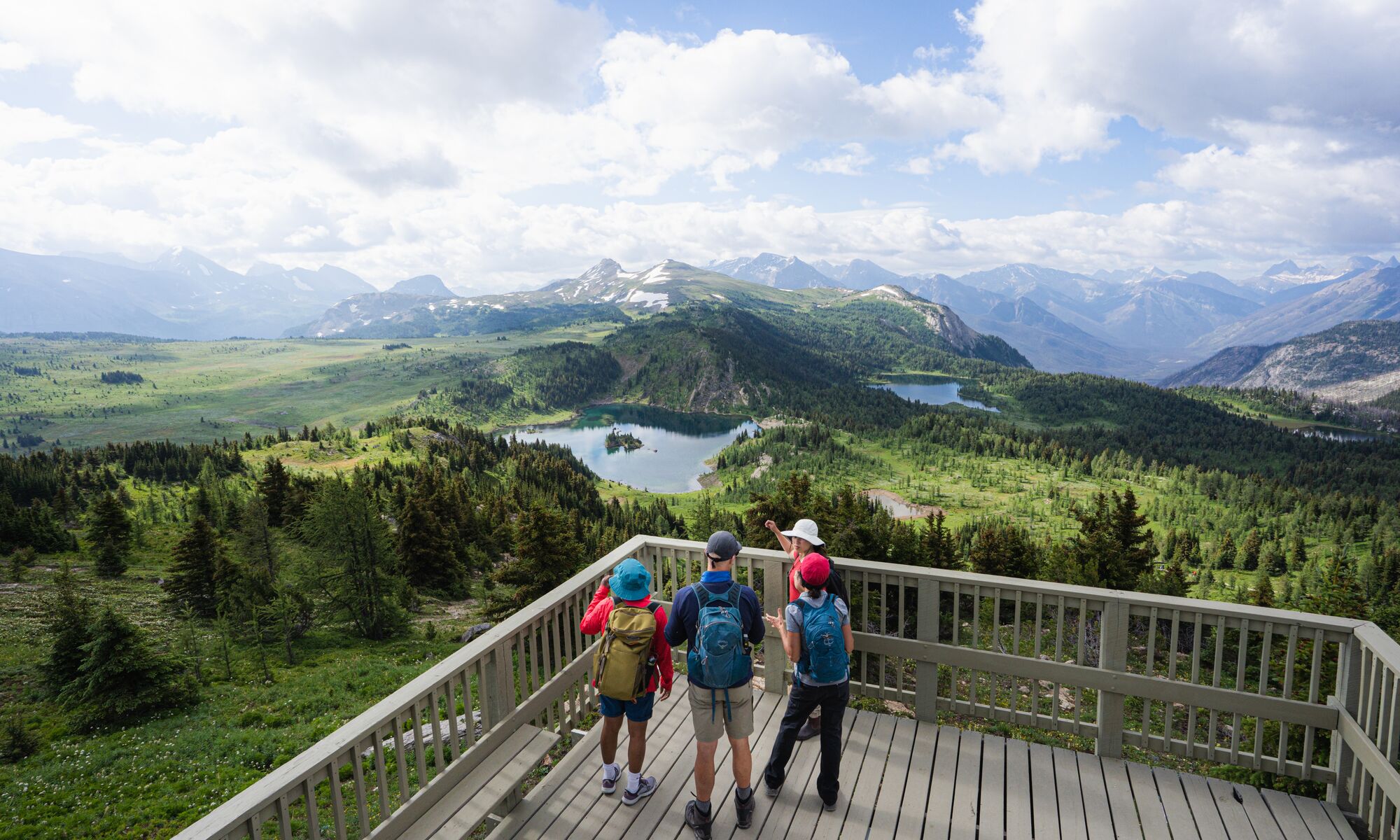 Four people on the Standish Viewing Deck at sunshine Meadows overlooking Rockbound Lake near Banff National Park.