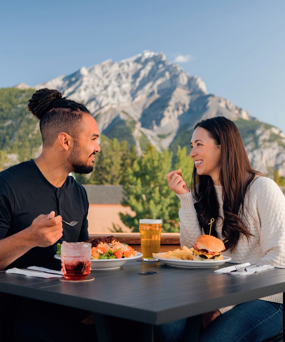 Couple dining on a rooftop patio in Banff with a mountain in the background.