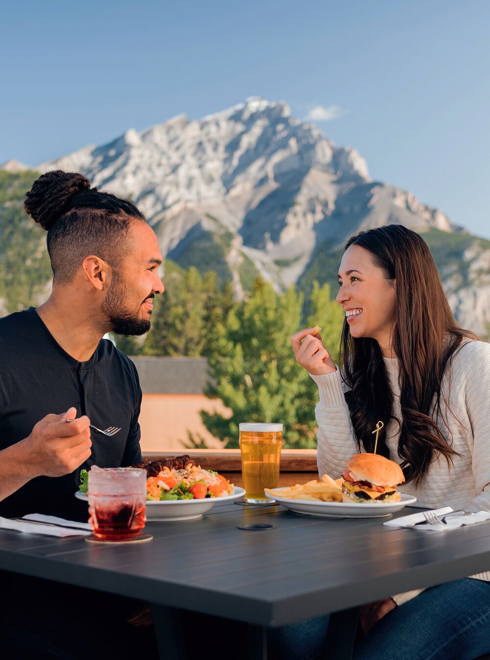 Two people enjoying a meal on the Rose and Crown Patio in the summer in Banff.