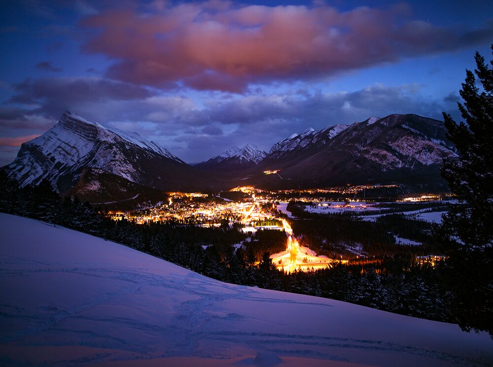 The Banff Townsite at night as seen from the Norquay Lookout on a dark winter night with Mt. Rundle in the background in Banff National Park.