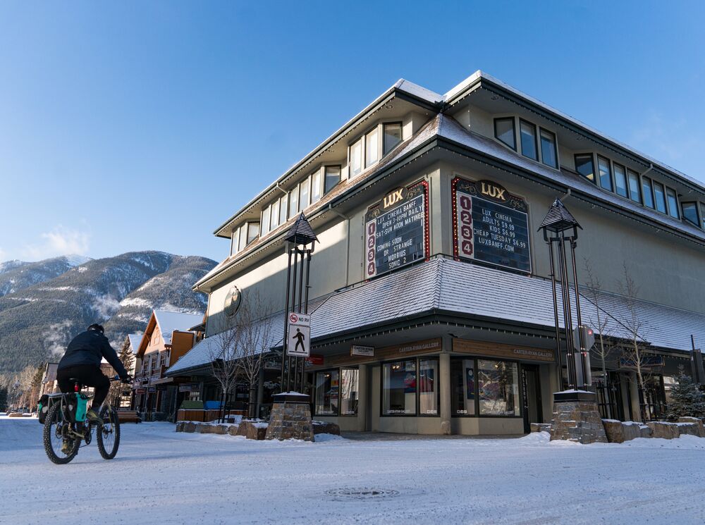 A cyclist bikes past the Lux Cinema in Banff during the winter.