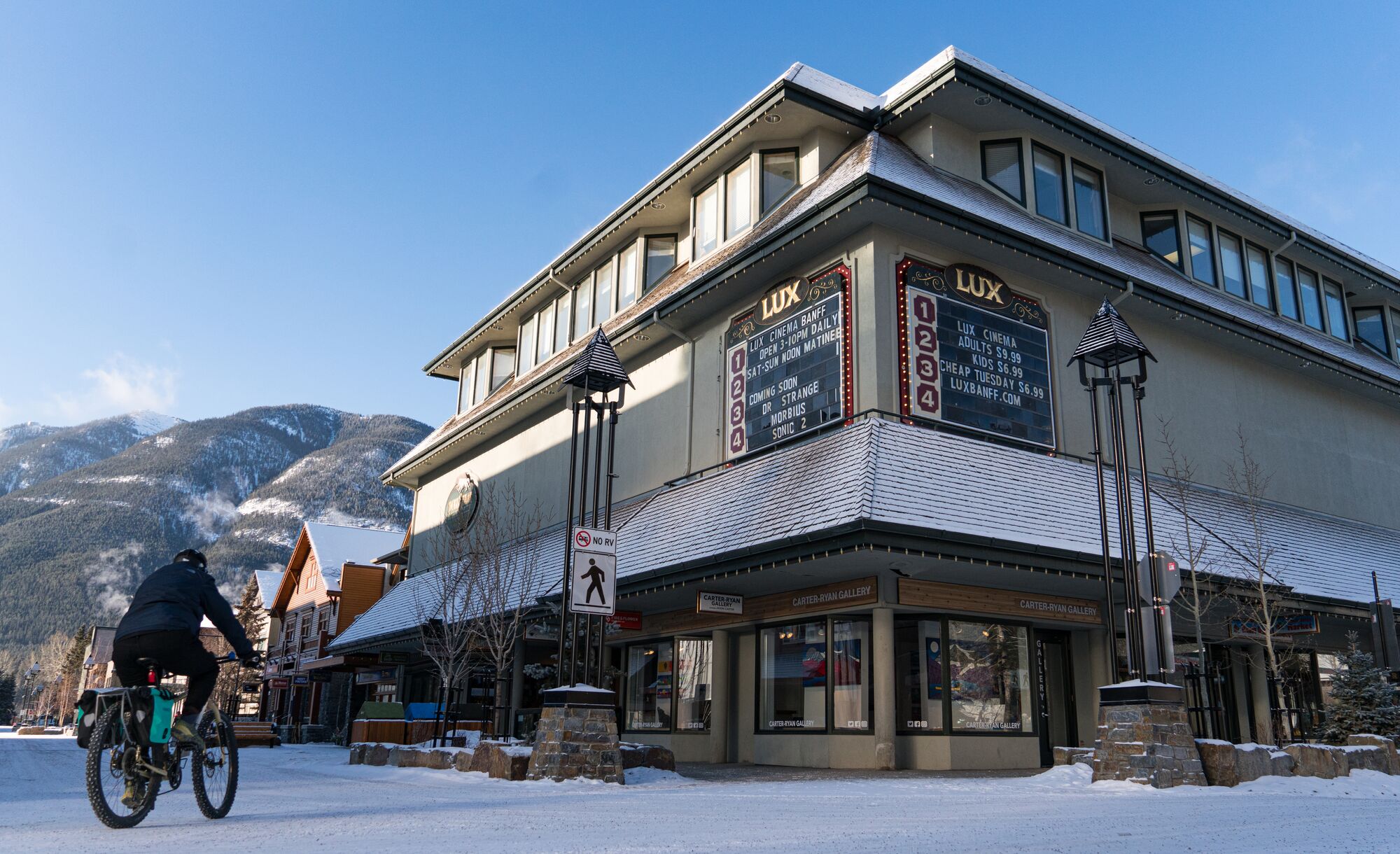 A cyclist bikes past the Lux Cinema in Banff during the winter.