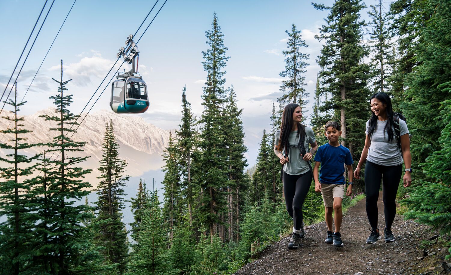 Two adults and a child hiking up Sulphur Mountain, a popular trail in Banff in July