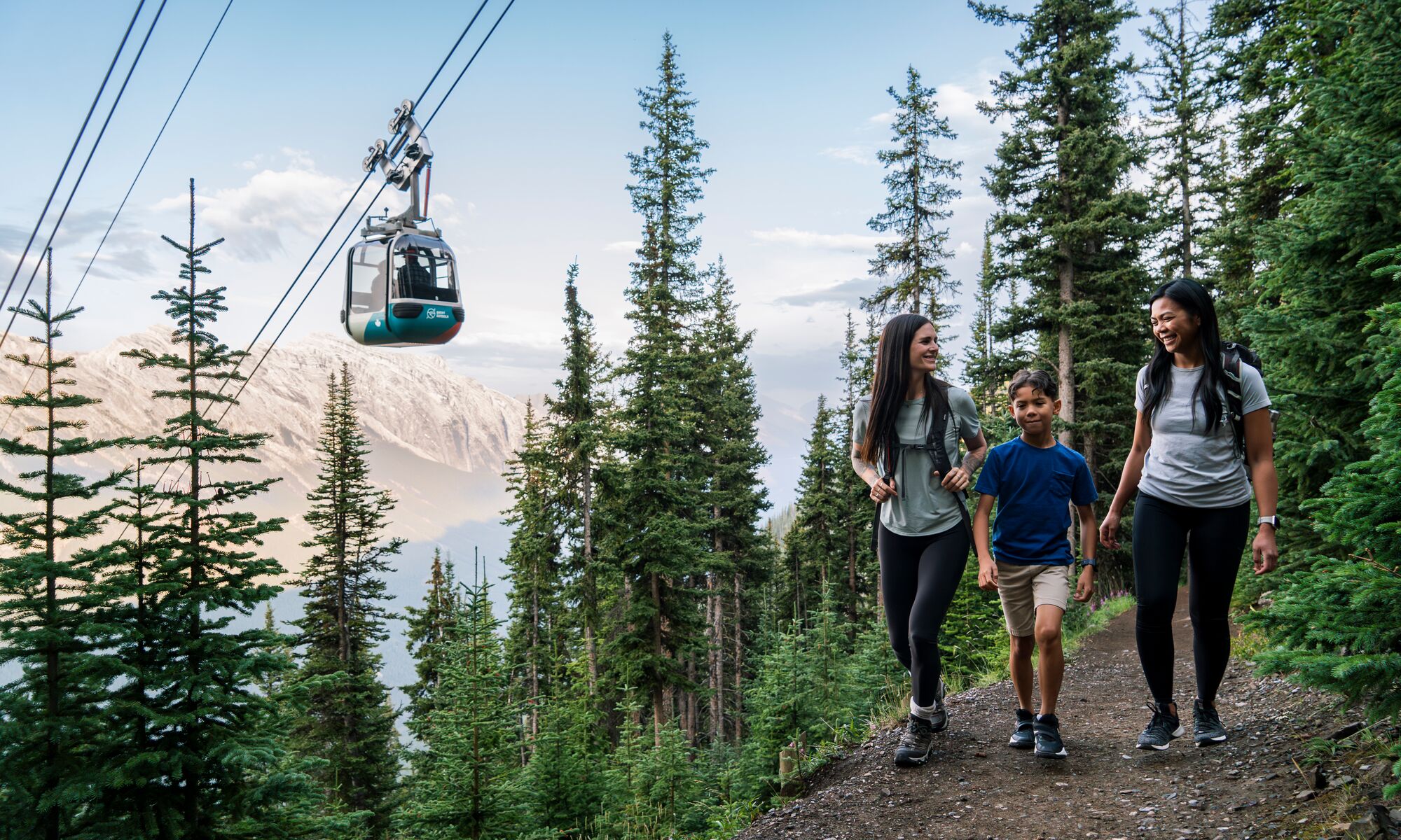 Two adults and a child hiking up Sulphur Mountain, a popular trail in Banff in July