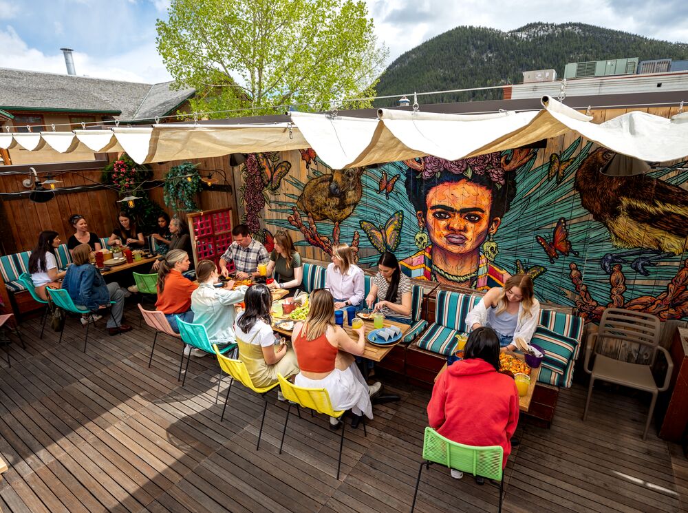 People sit in the sunshine on El Patio, a rooftop terrace bar, in Banff.