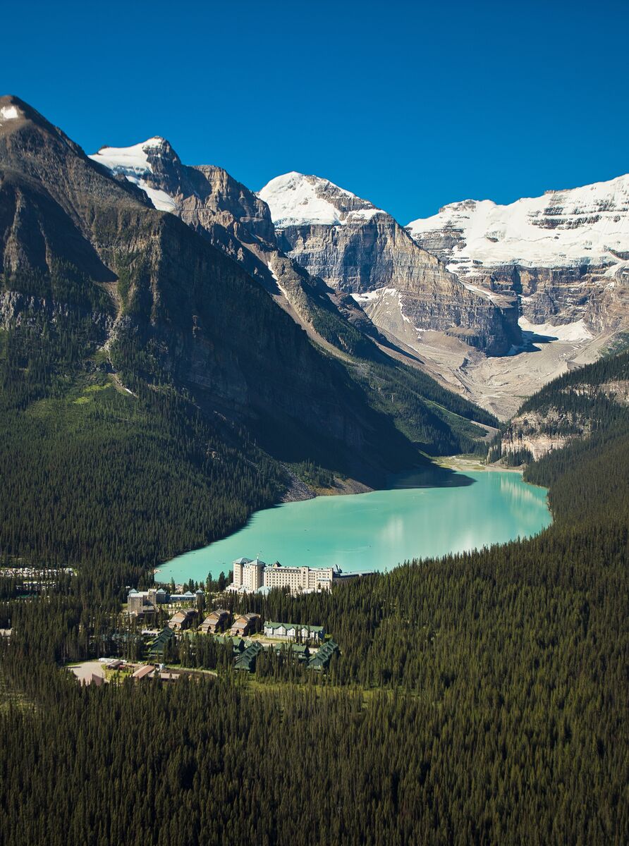 An aerial view of Lake Louise and the Fairmont Chateau Lake Louise on a clear day with snow-capped peaks