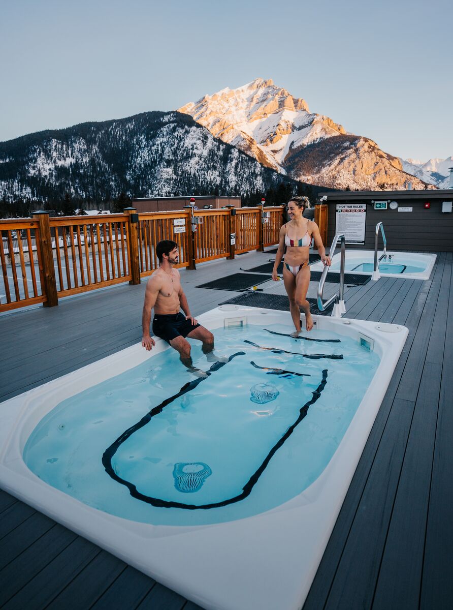 Two people on a rooftop hot tub at Basecamp suites in Banff.