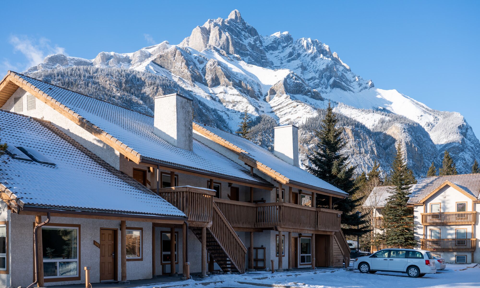 A hotel with Cascade Mountain in the background and everything covered in snow.