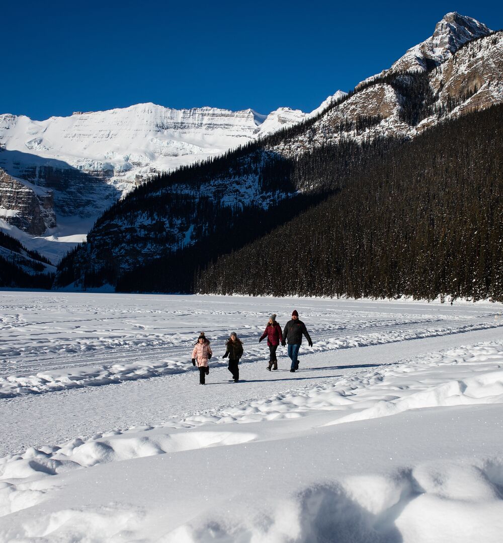 A family hiking along the Lake Louise lakeshore trail in the winter