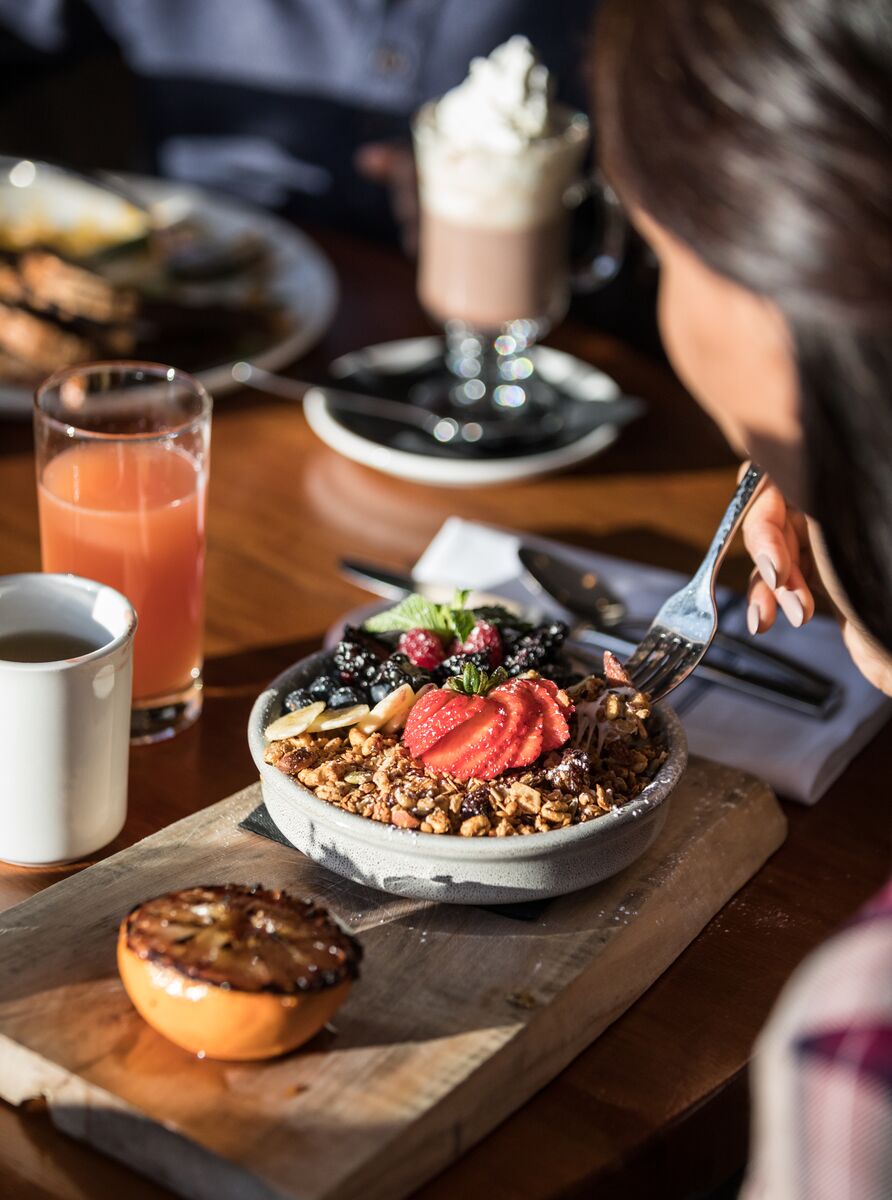 A breakfast bowl of muesli and yogurt and fruits on a wooden board at the Juniper Bistro in Banff National Park.