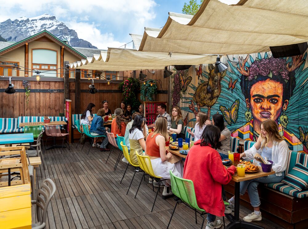 A group of people on a rooftop patio, one of th best things to do in Banff in June