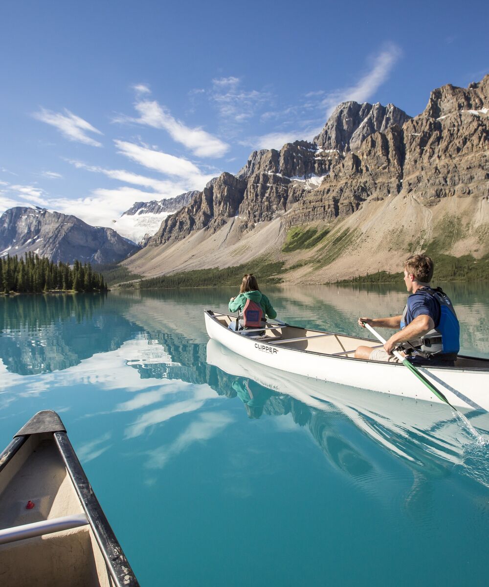 Two canoes paddling on Bow Lake on a blue sky summer day
