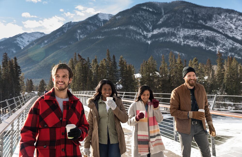 Group of friends walking around Banff with hot chocolates in hand.