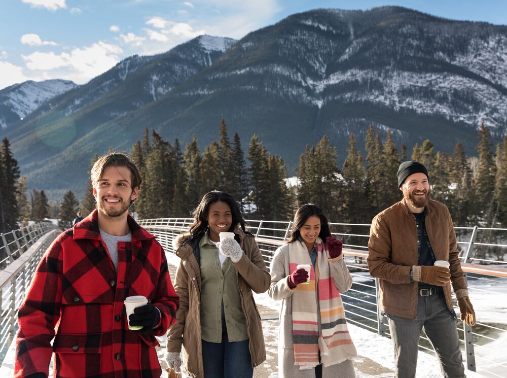Group of friends walking around Banff with hot chocolates in hand.