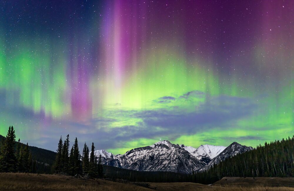 The aurora dances over a mountain in Banff National Park on a spring night.