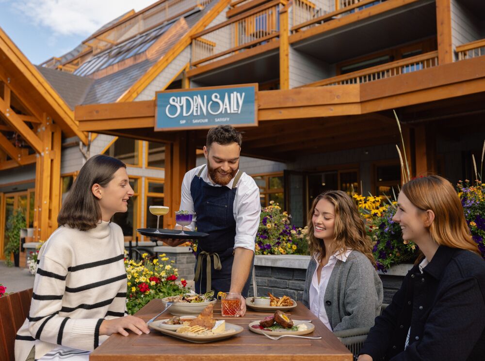 People sitting on an outdoor patio in Banff National Park with food and drinks