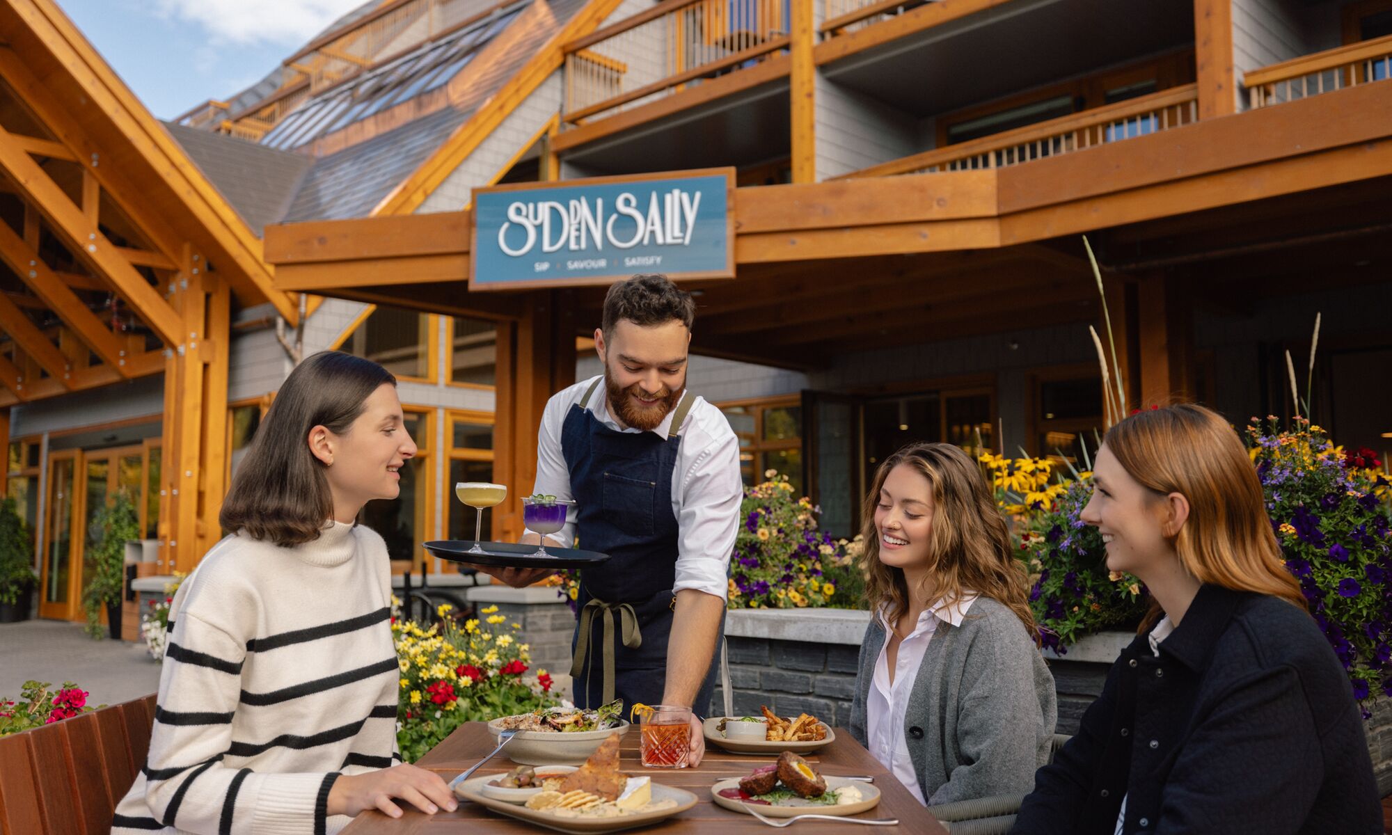 People sitting on an outdoor patio in Banff National Park with food and drinks