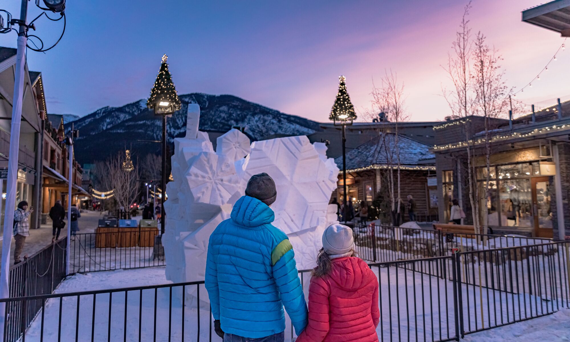 A couple looks at a snow sculpture at sunset on Bear Street during the SnowDays Festival in Banff and Lake Louise.