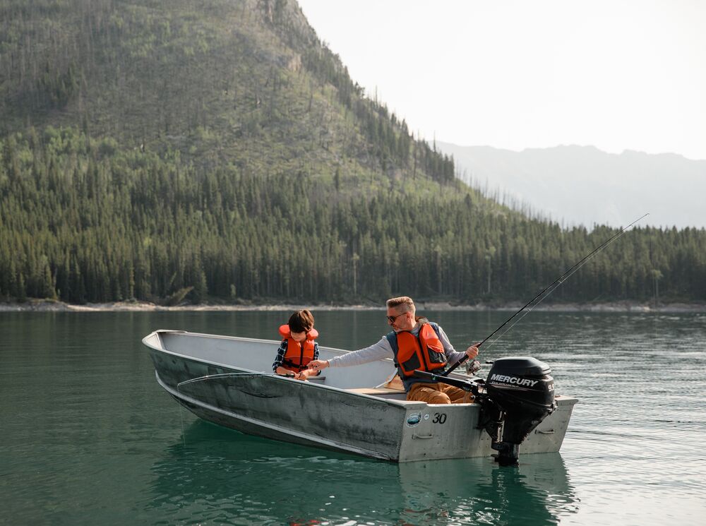 A father and son fishing on Lake Minnewanka in a small motor boat