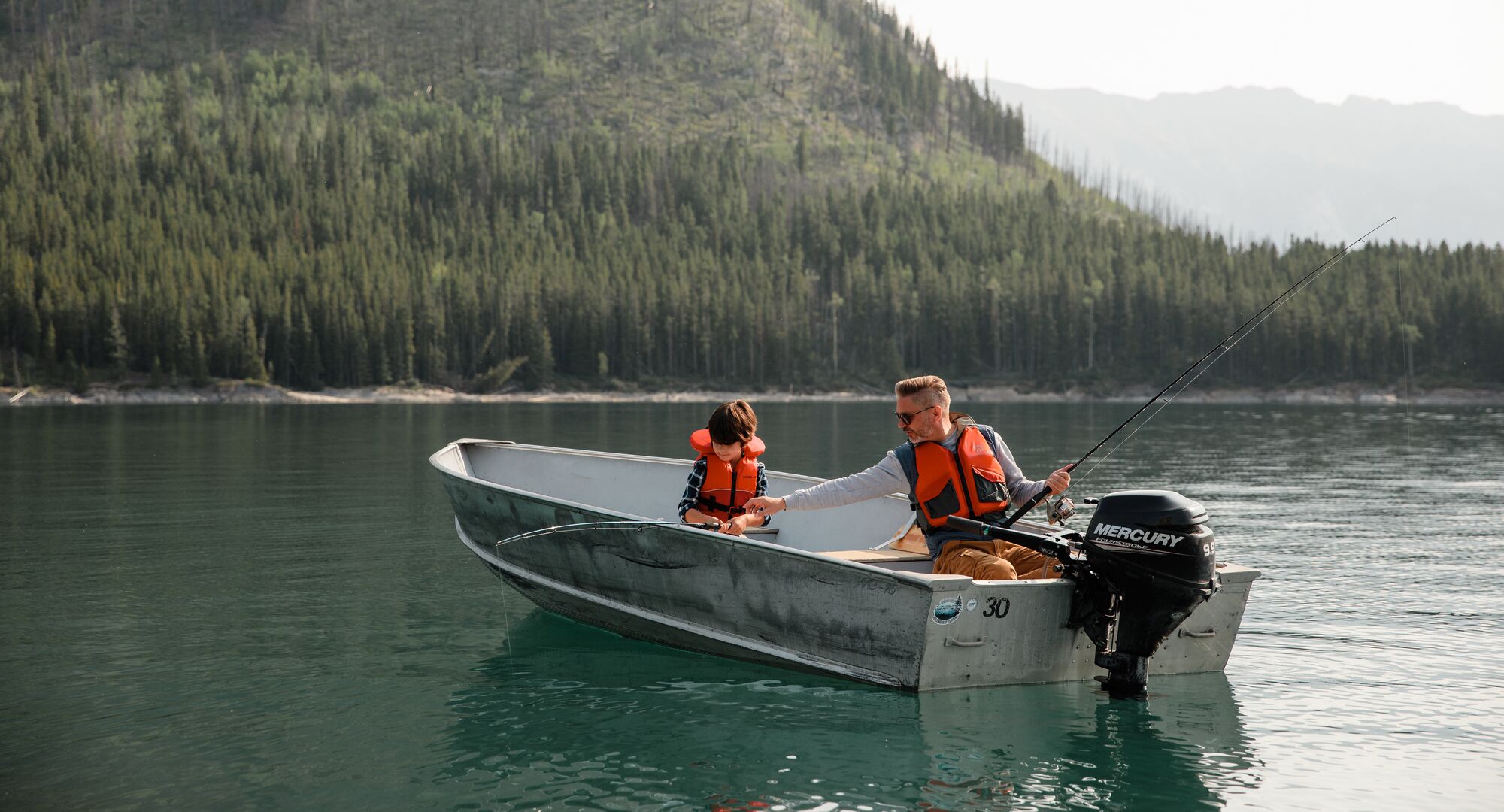 A father and son fishing on Lake Minnewanka in a small motor boat