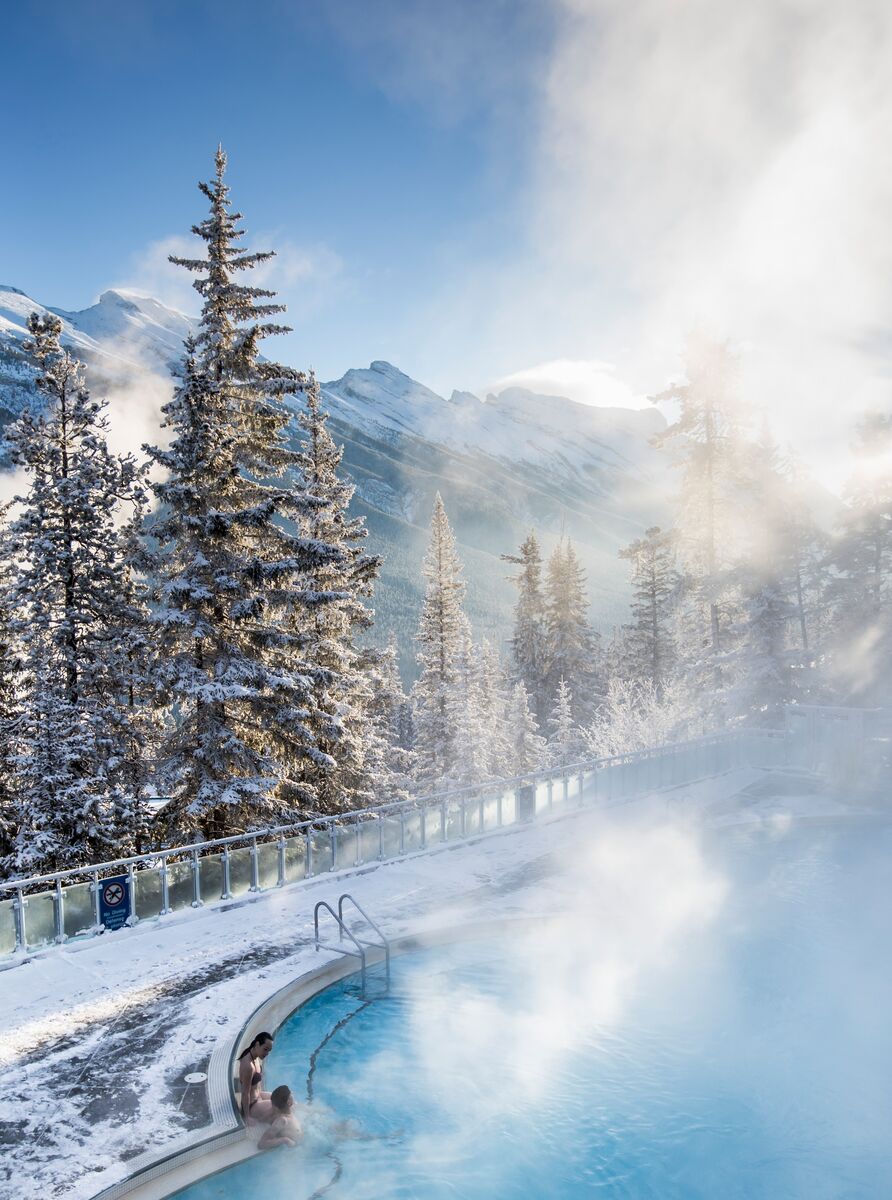 Two people sit in the Banff Upper Hot Springs in the winter.
