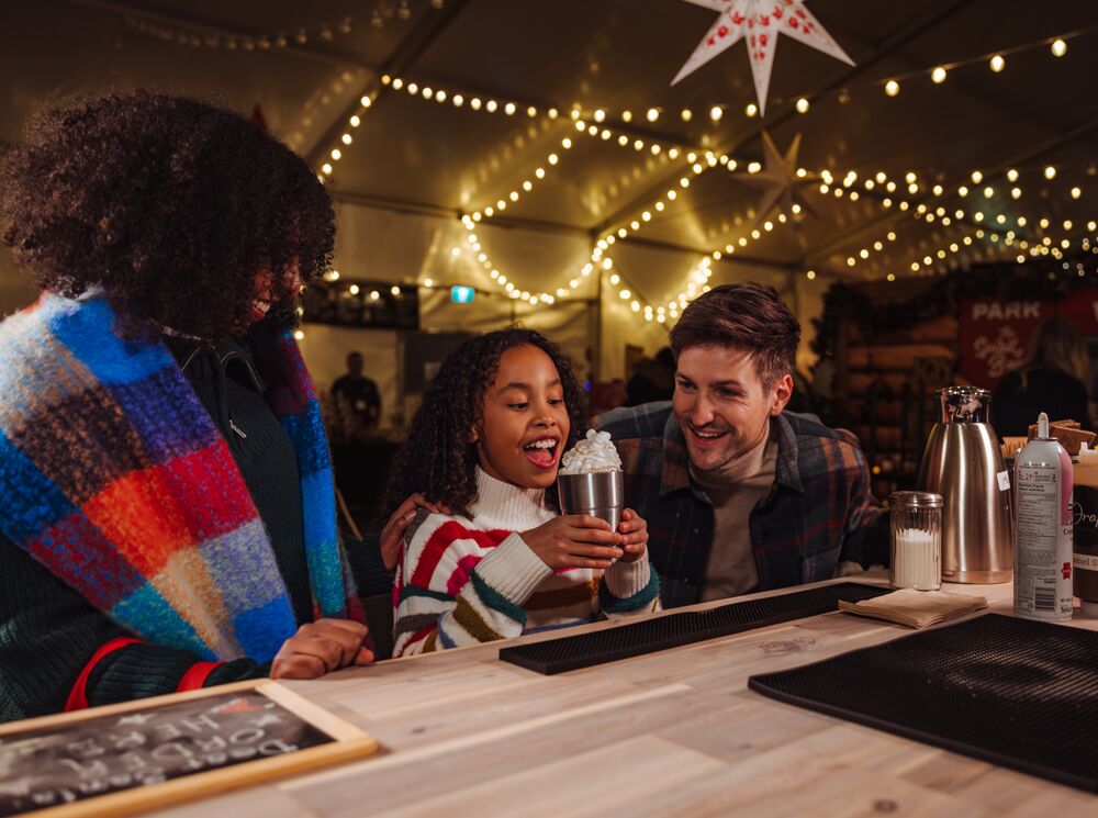 A family enjoys a hot chocolate at the Banff Christmas Market in Banff National Park.