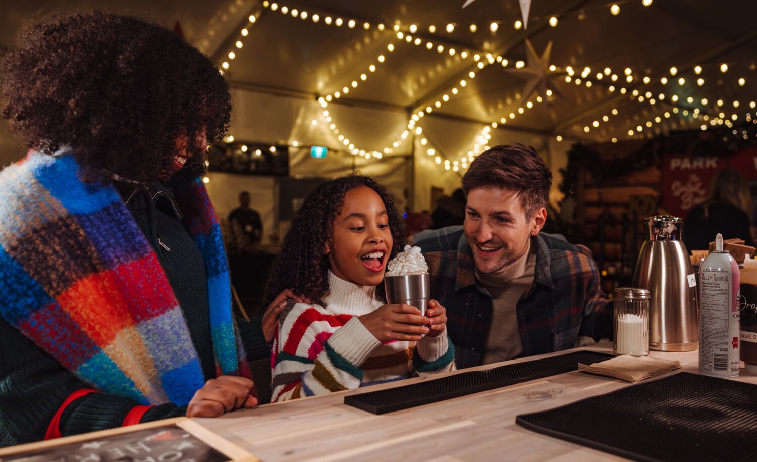 A family enjoys a hot chocolate at the Banff Christmas Market in Banff National Park.