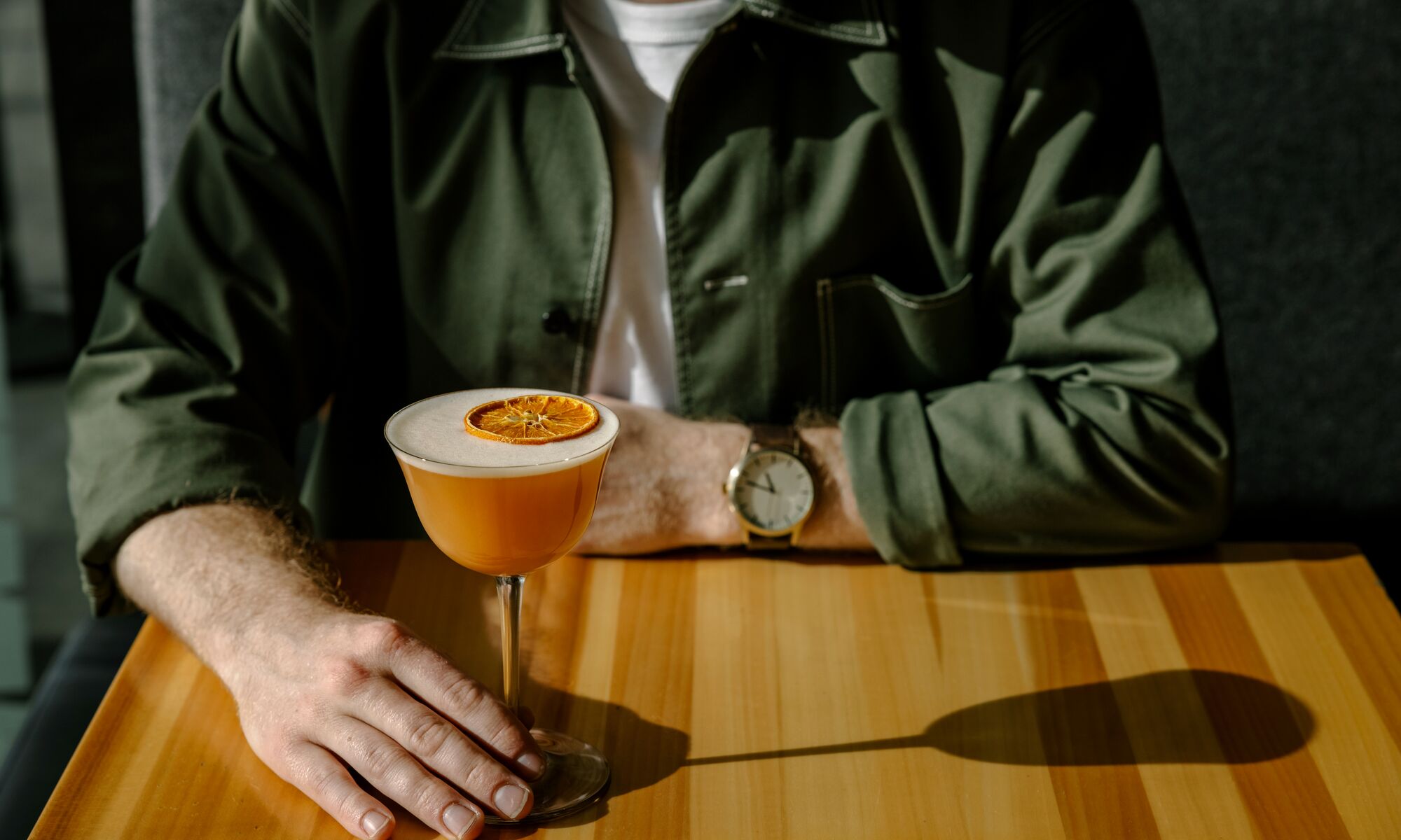 A person enjoys a drink while looking at the Sundance Range from Sky Bistro