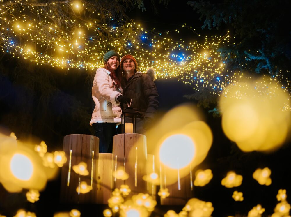 A couple walking through a lit up Cascade of Times Garden for In Search of Christmas Spirit in Banff