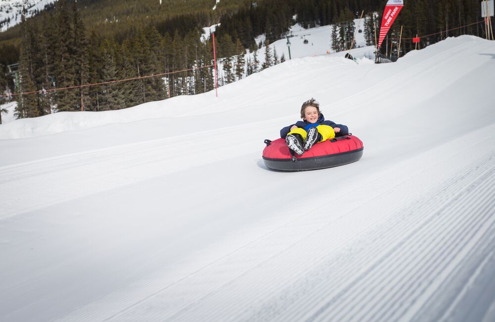 A kind whizzing down a snow slope in a tube at the Lake Louise Ski Resort