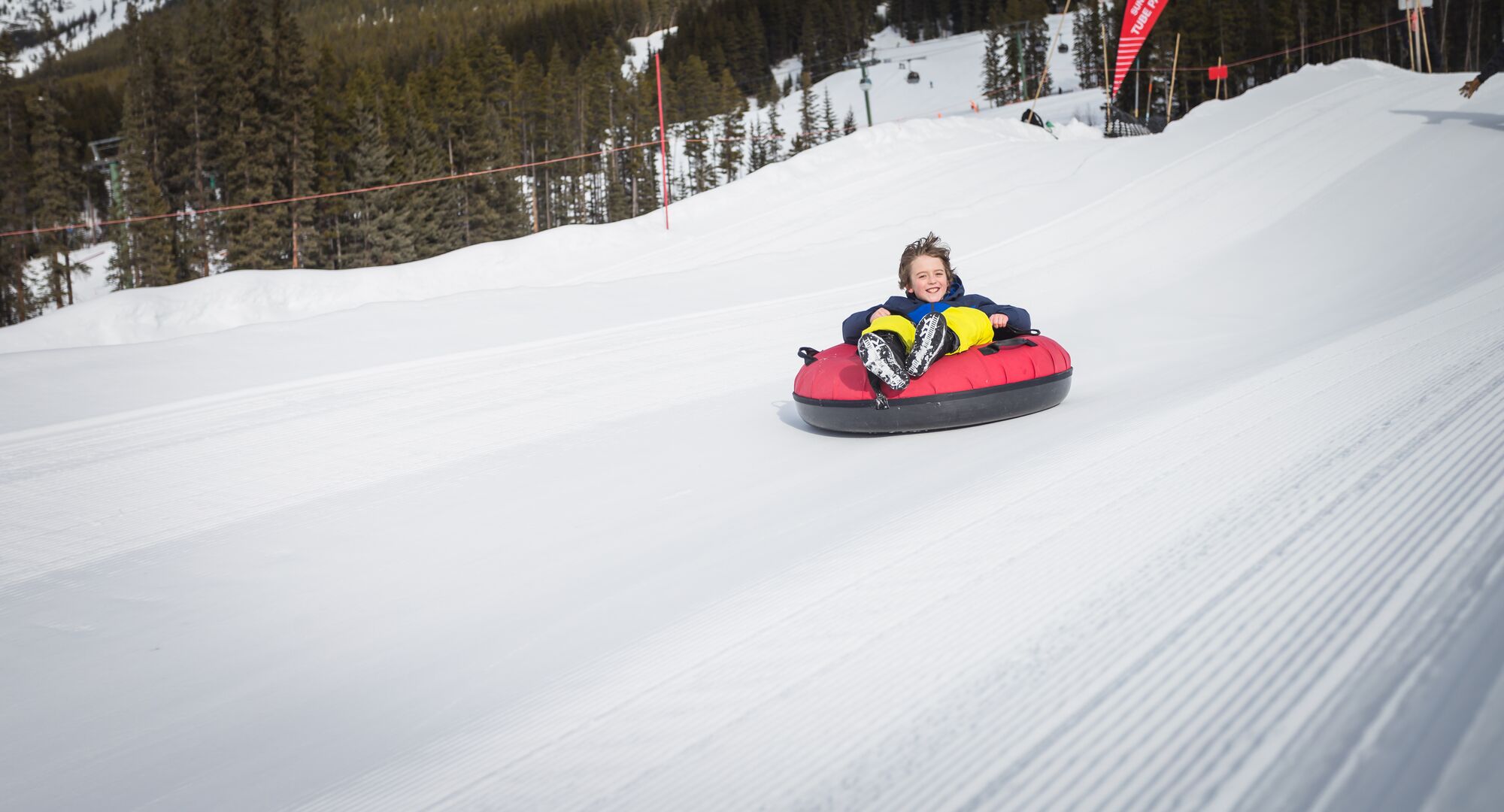 A kind whizzing down a snow slope in a tube at the Lake Louise Ski Resort