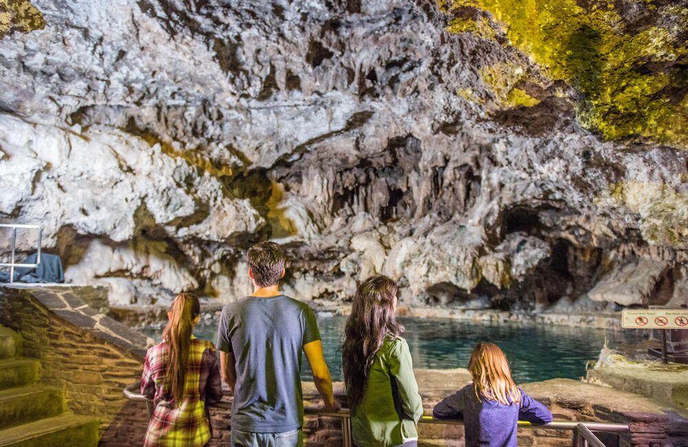 Family of four looking at the spring in the Cave at the Cave & Basin National Historic Site