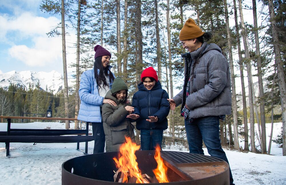A family warming up by the fire after a winter adventure in Banff National Park