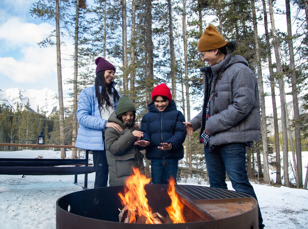 A family warming up by the fire after a winter adventure in Banff National Park