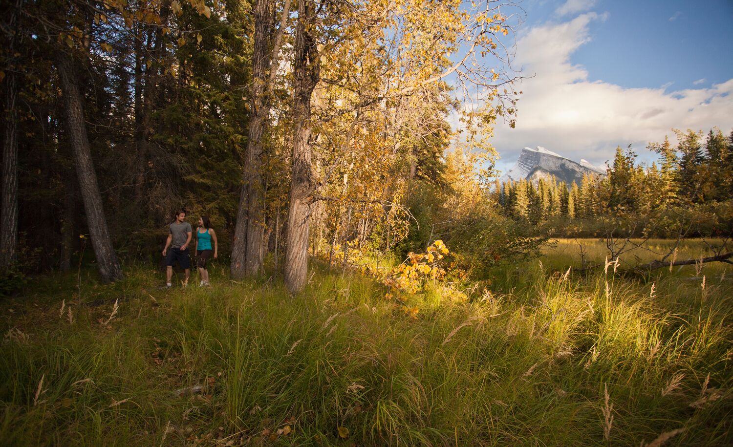 A couple walks in the trees on the Fenlands Trail in Banff.
