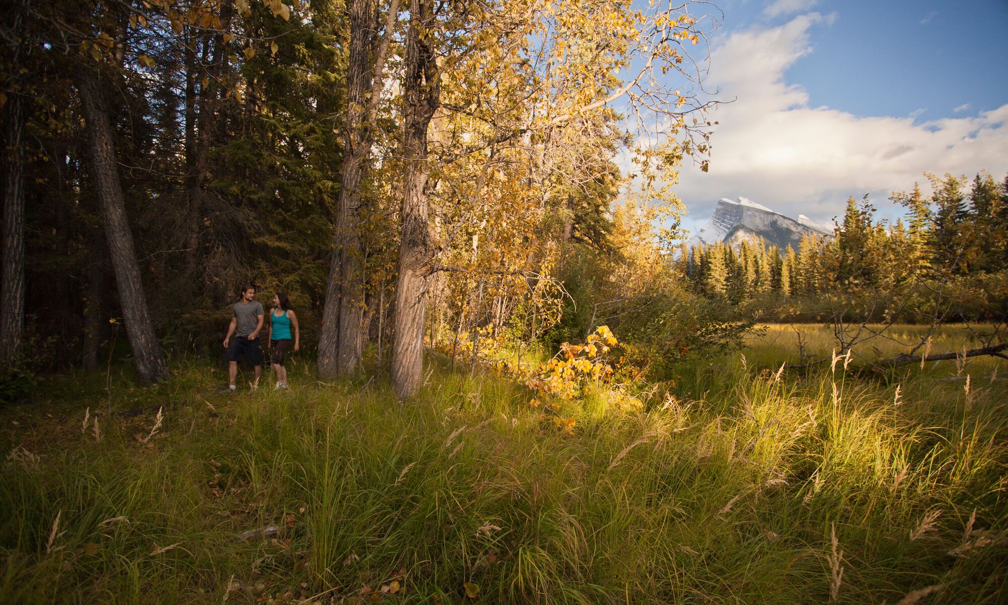 A couple walks in the trees on the Fenlands Trail in Banff.