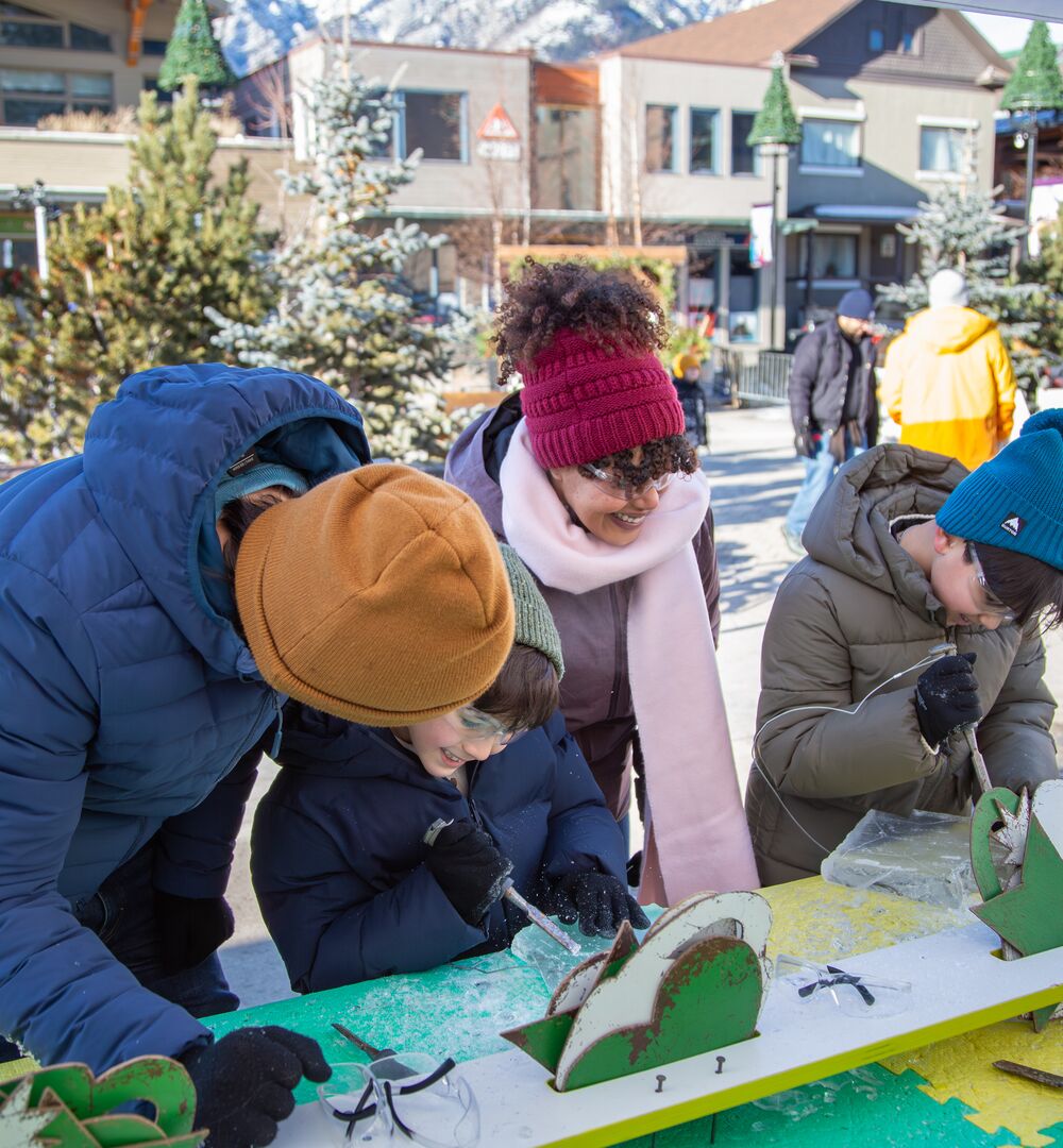 A family trying out ice carving at the Weekend of Wonder at SnowDays in Banff
