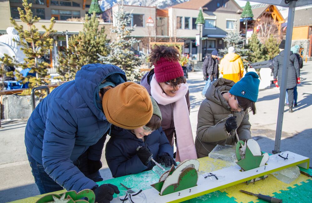 A family trying out ice carving at the Weekend of Wonder at SnowDays in Banff