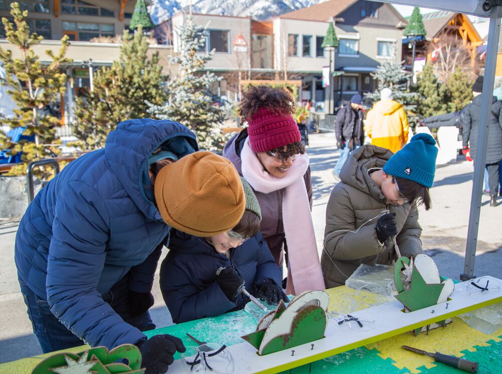 A family trying out ice carving at the Weekend of Wonder at SnowDays in Banff