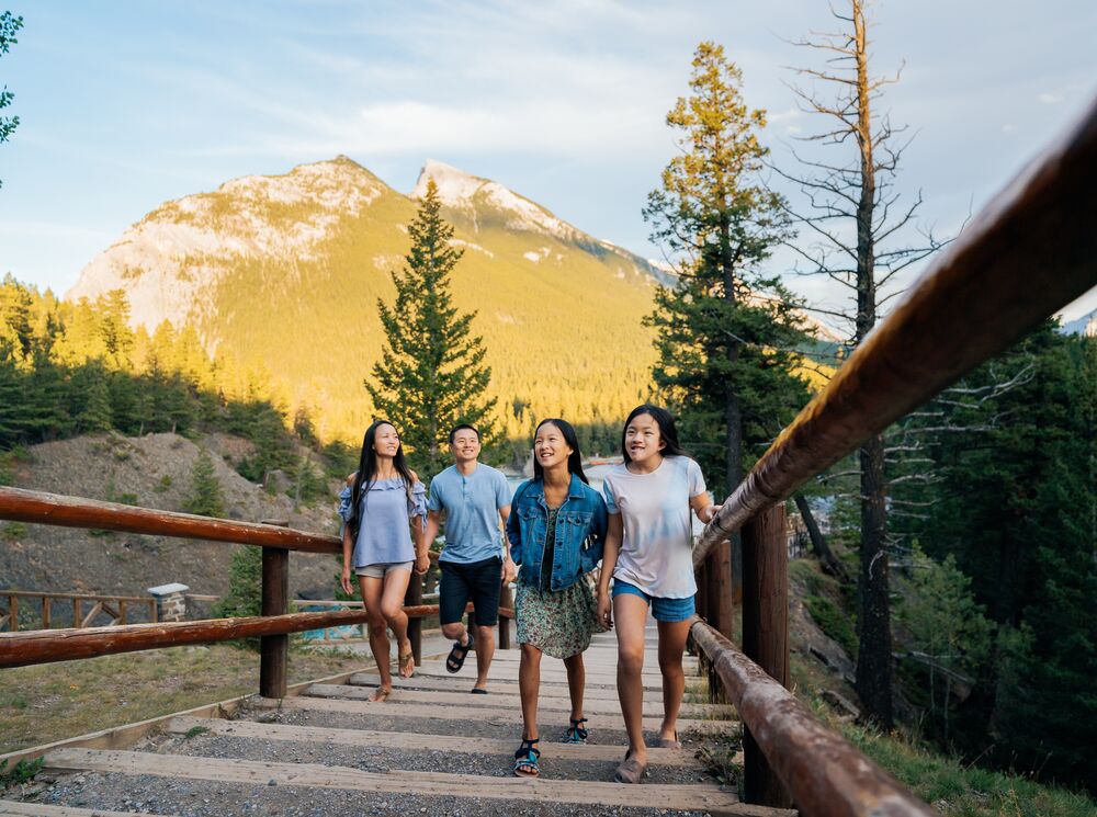 A family of four walking along the Bow River, a popular thing to do in Banff National Park